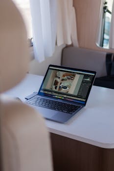 Laptop on a desk with creative work displayed, in a cozy and well-lit space.