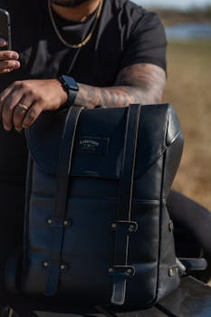 A cool leather backpack held by a tattooed man, showcasing modern urban fashion style.