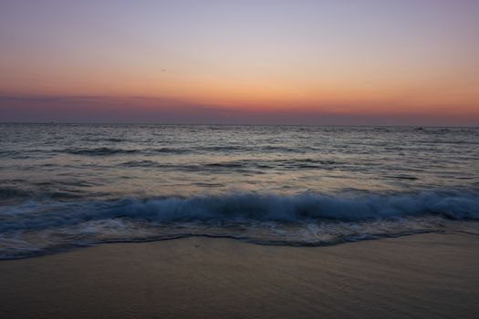 Calm ocean waves under a vivid sunset sky creating a tranquil coastal scene.