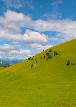 Picturesque green hillside under a vibrant blue sky in Selva di Val Gardena, Italy.