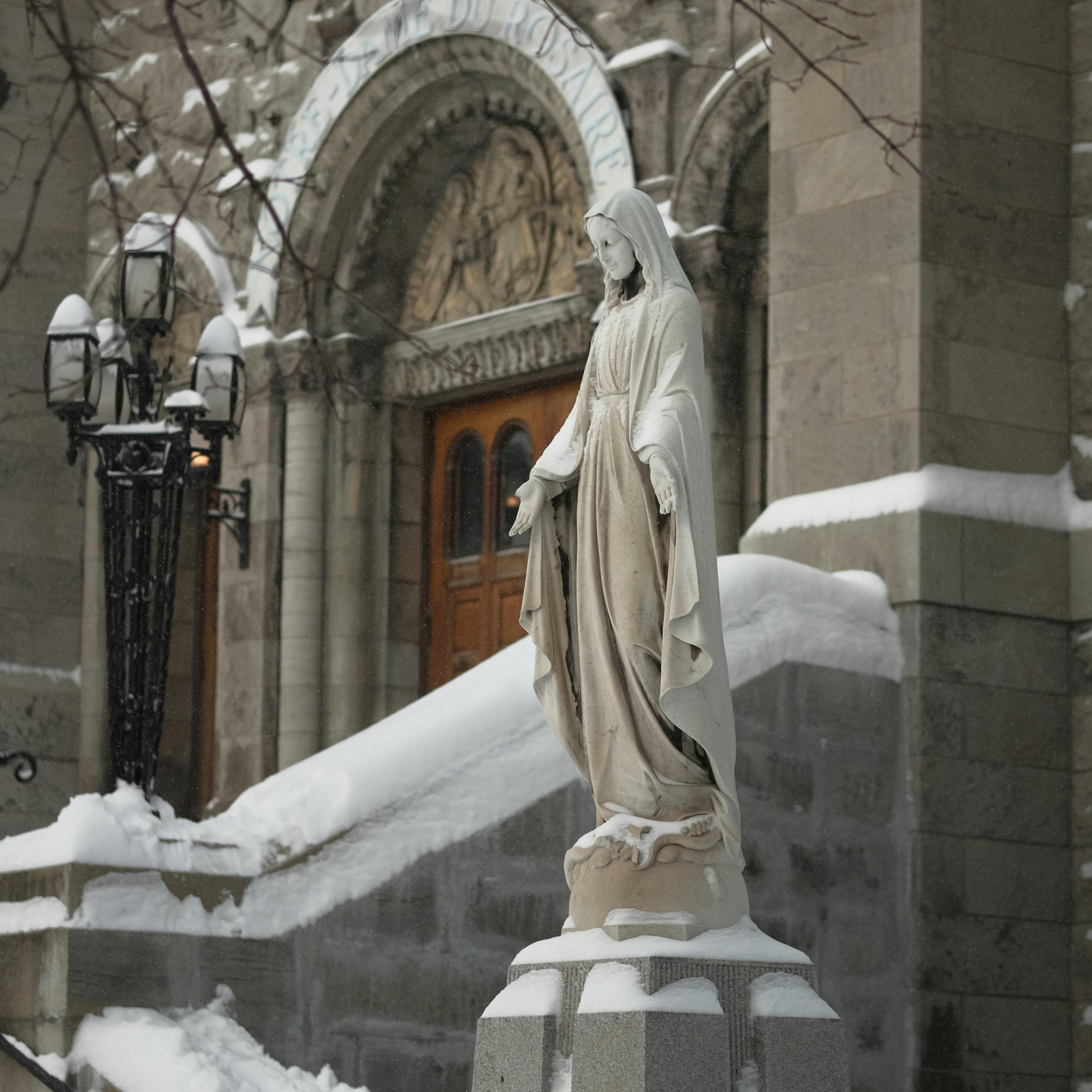 Statue of Standing Virgin Mary in front of Church in Winter