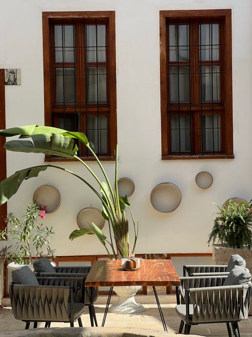 Free Cozy outdoor café setting with stylish furniture and lush greenery. Stock Photo