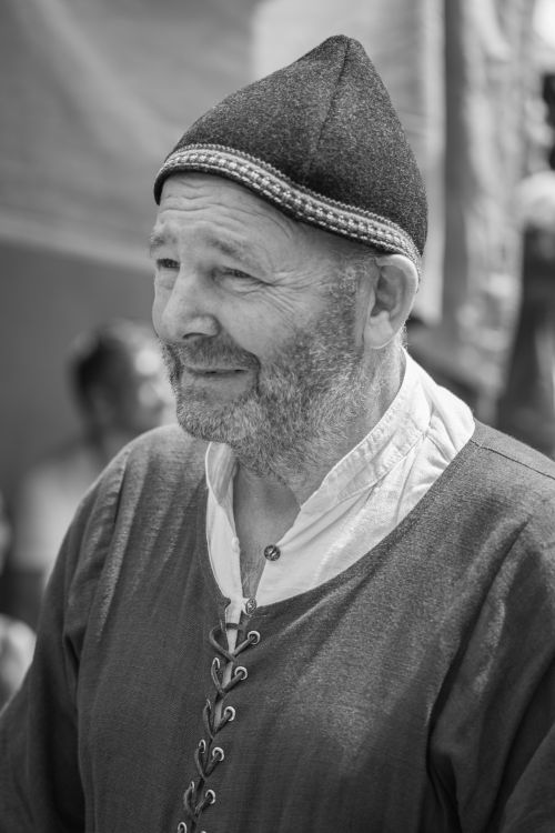 Free A black and white portrait of an elderly man wearing medieval clothing and a beanie hat. Stock Photo