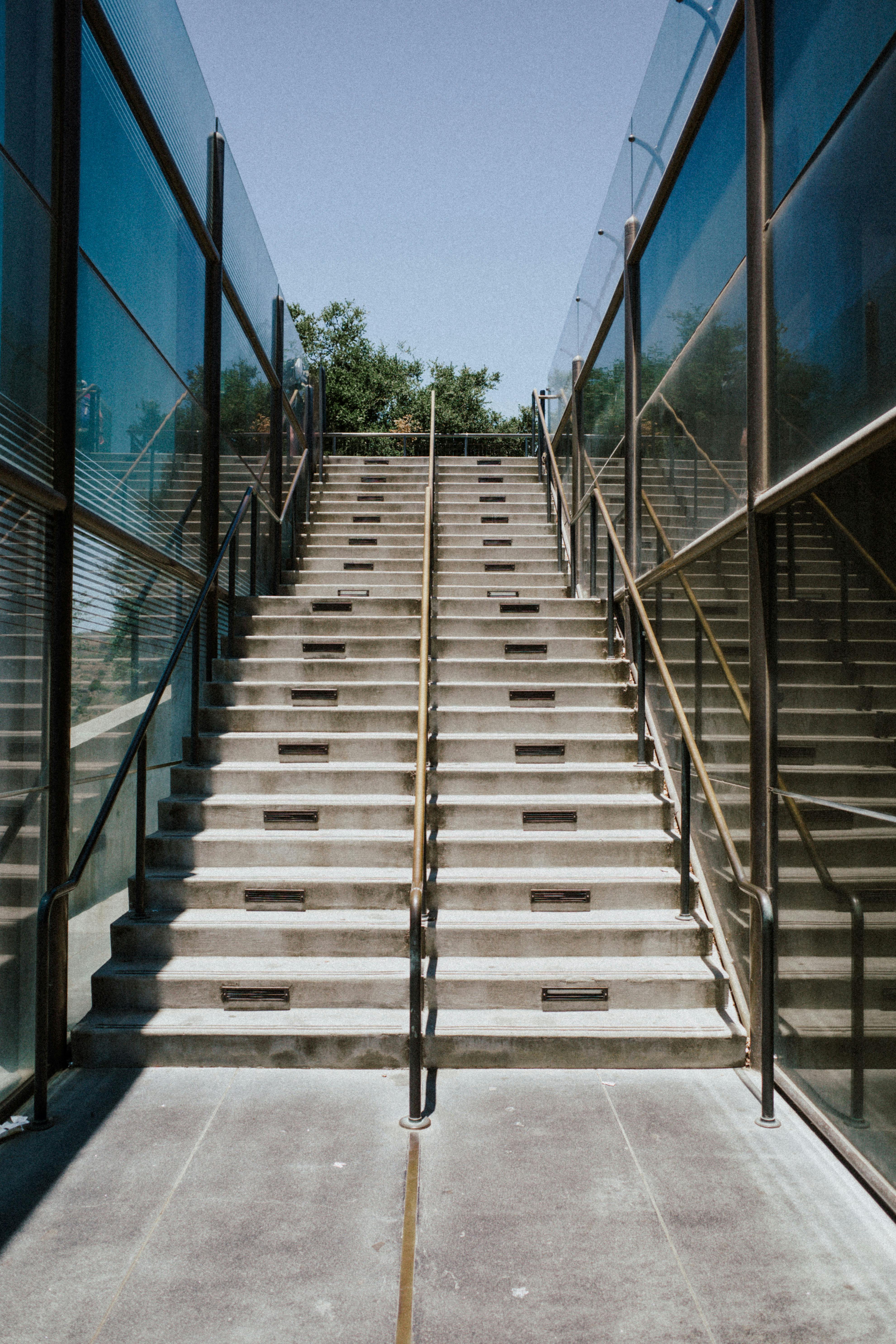 Staircase leading between glass walls reflecting urban architecture in West Hollywood.