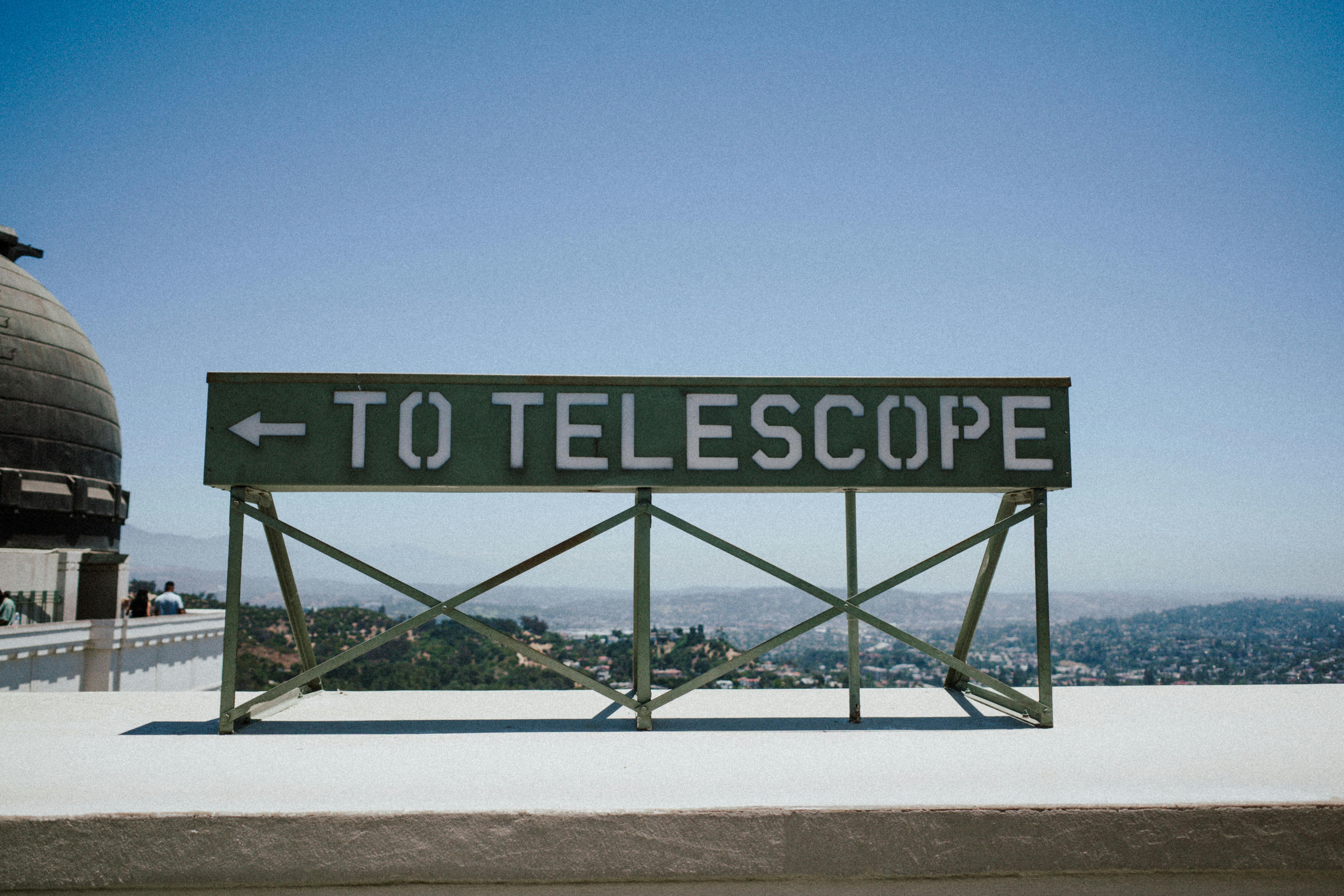 To Telescope sign at Griffith Observatory overlooking Los Angeles, CA skyline.