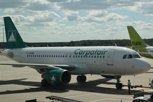 Carpatair Airbus A319 on airport apron in Mārupe, Latvia under sunny skies.