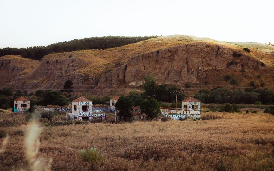 Explora los pintorescos edificios abandonados ubicados en el paisaje rural de Madrid, rodeados de colinas y prados.