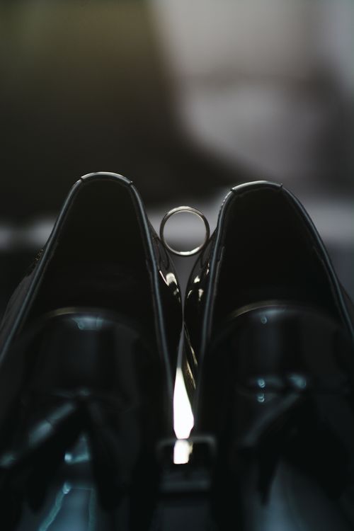 Free Stylish black loafers with a wedding ring resting between them, captured in a soft moody light. Stock Photo