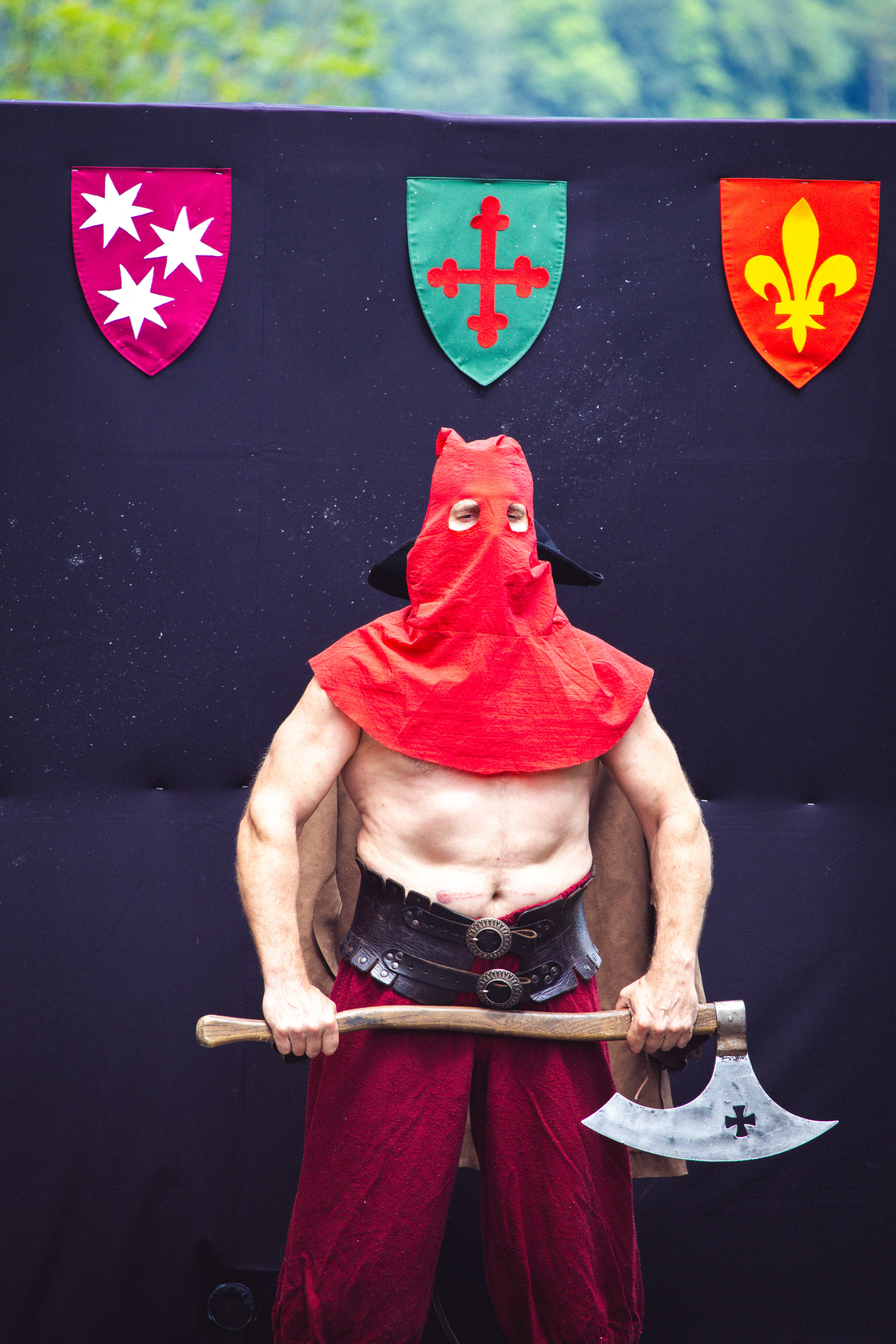 A performer in a medieval executioner costume posing with an axe during a festival.