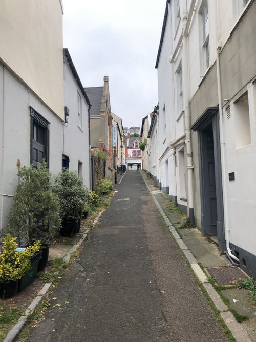 Free Quiet, charming narrow street in Devon, England, lined with quaint townhouses and potted plants. Stock Photo