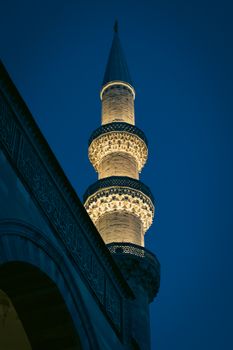 The beautifully lit minaret of Suleymaniye Mosque in Istanbul showcases stunning Islamic architecture against a dark blue sky.