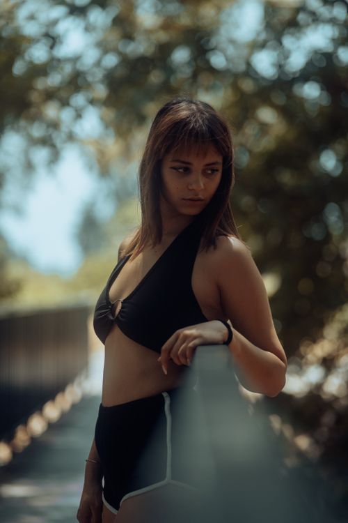 Free Stylish woman in black outfit posing by a handrail in a park setting under soft daylight. Stock Photo