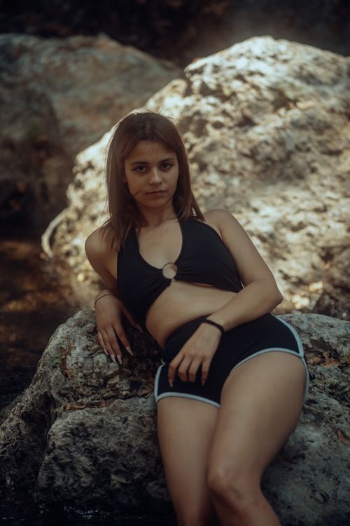 Free Fashion model in black top and shorts posing on rocky terrain. Stock Photo