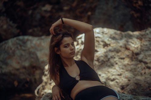 Free A fashionable woman in a black top striking a pose outdoors against a rocky backdrop. Stock Photo