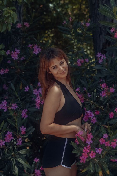 Free A woman wearing a black outfit poses surrounded by vibrant flowers in a natural setting. Stock Photo
