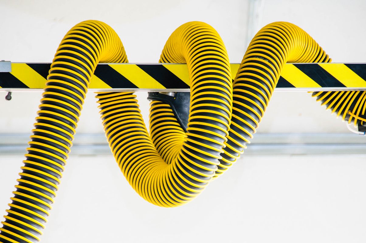 Coiled yellow industrial hose in a safety-colored industrial setting