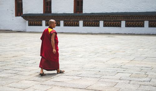 Free A Buddhist monk in traditional attire walks through a courtyard in Bhutan, showcasing spiritual tranquility. Stock Photo