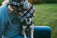 戴着格子帽的人和小狗坐在草地上，瞬间的爱意被捕捉到了