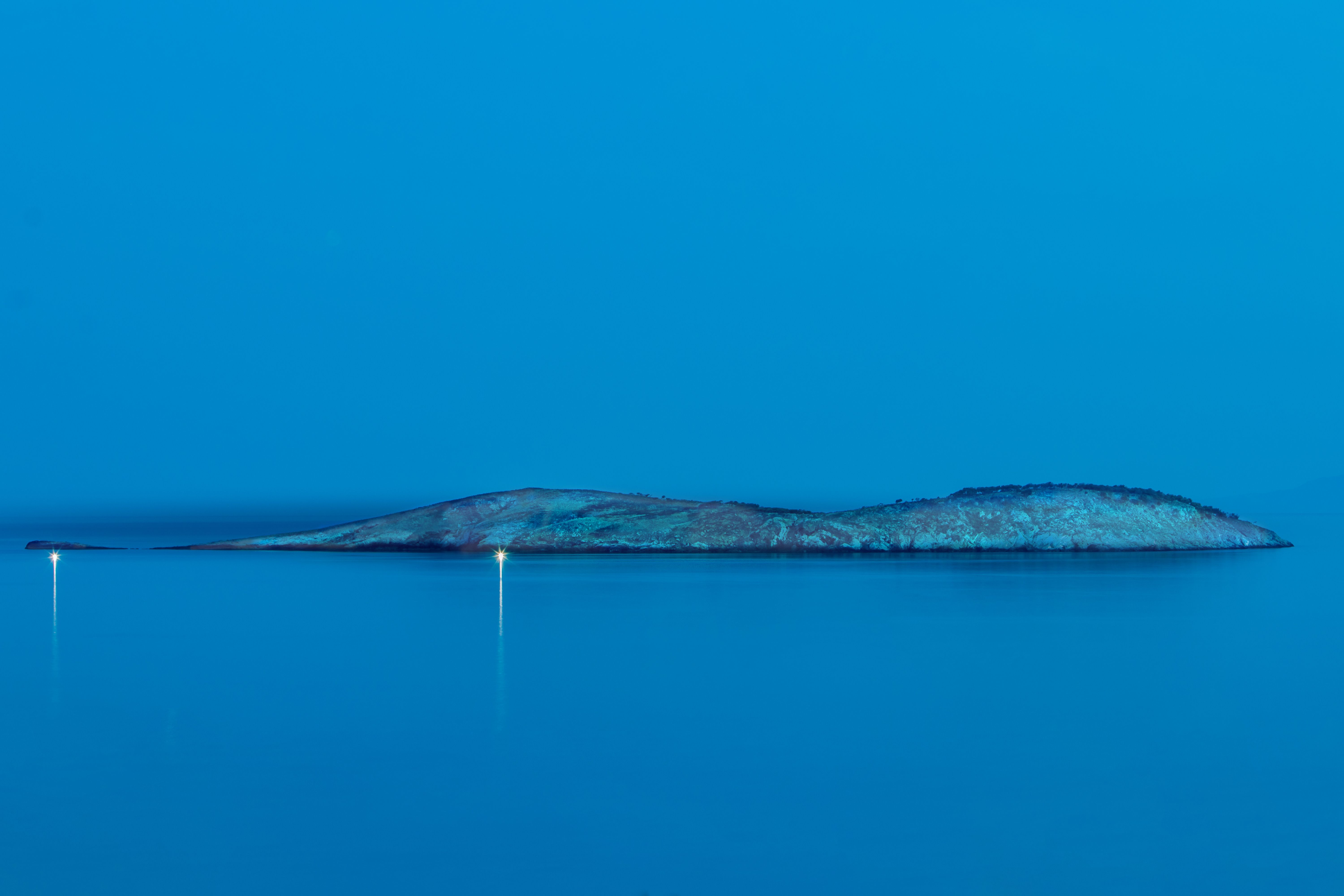 Paysage maritime serein avec une petite île, créant une ambiance paisible en soirée.