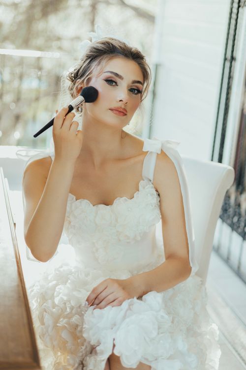 Female Model Wearing a White Dress Using a Makeup Brush  Free Stock Photo