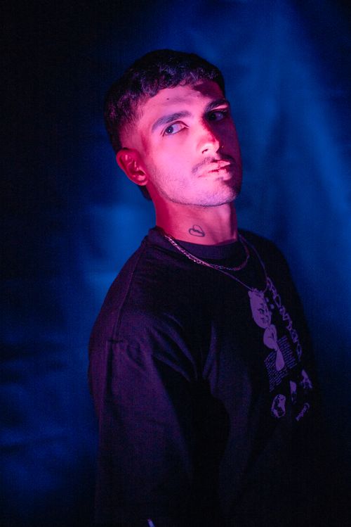 Free A young man poses in vibrant neon lighting, embodying modern fashion and style. Stock Photo