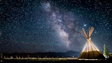 在星空下的圆锥形帐篷里，银河的迷人景色非常适合天文爱好者