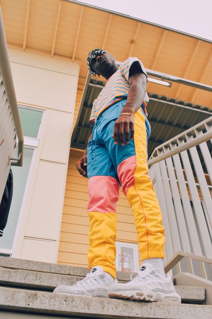 Stylish man in vibrant streetwear posing outdoors for a fashion shoot.