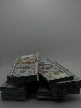 Piles of US hundred dollar bills stacked, representing wealth and finance.