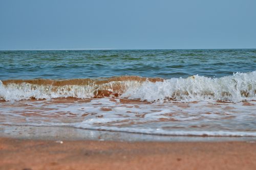 Free Serene beach scene with gentle waves lapping against the sandy shore under a clear sky. Stock Photo