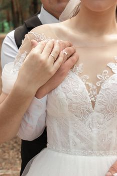 Close-up of newlyweds holding hands in a beautiful wedding dress and suit, reflecting love and commitment.