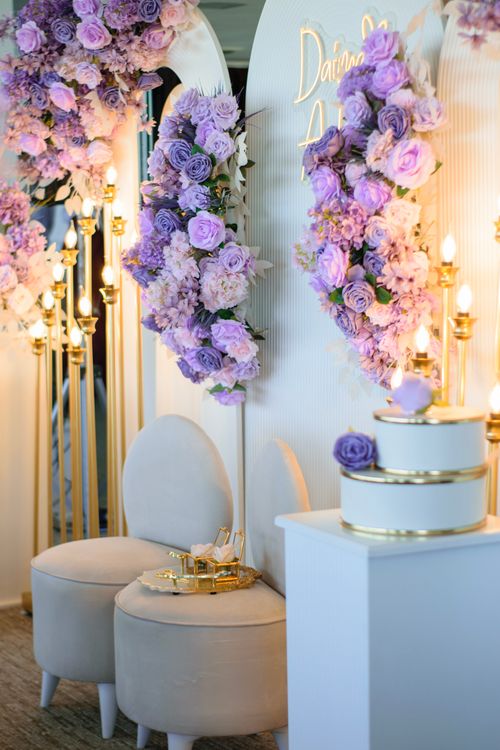 Free Lavish wedding decor with purple roses, elegant chairs, and a tiered cake. Stock Photo