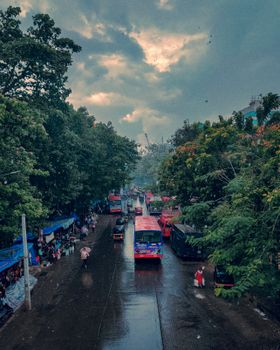 A bustling urban street in Maharashtra during a rainy day, featuring traffic and market activity.