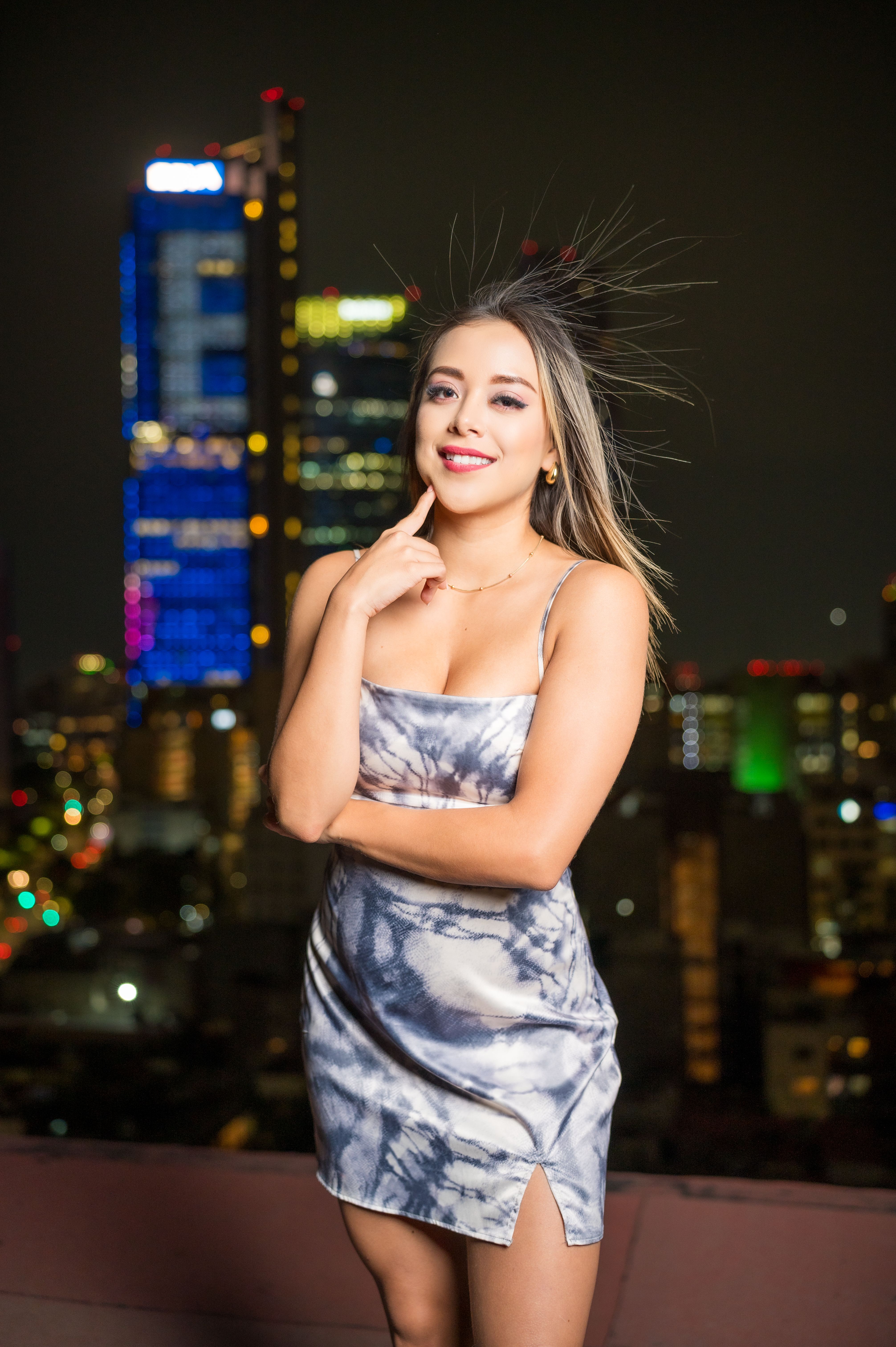 Model posing in a chic dress against the nighttime skyline of Ciudad de México, exuding urban elegance.