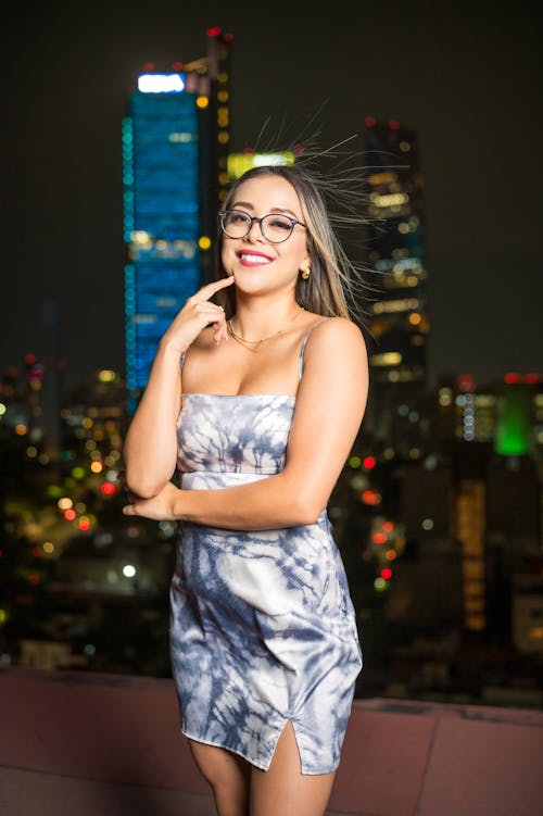 A woman in a dress and glasses posing for a photo