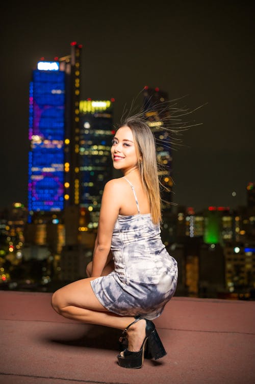 A woman in a dress is posing on a rooftop