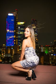 Stylish woman posing at night with the skyline of Ciudad de México, adding urban fashion flair.