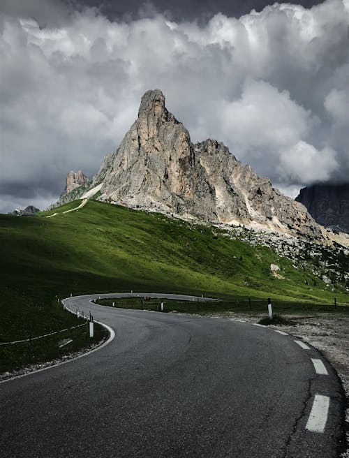 Mountain Near Green Grass Field and Asphalt Road