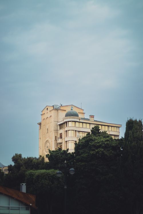 Free Photo of a historic building surrounded by greenery under a clear sky. Stock Photo
