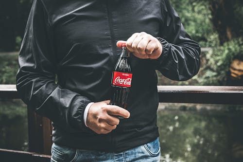Man in Black Jacket Holding Bottle of Coca-cola