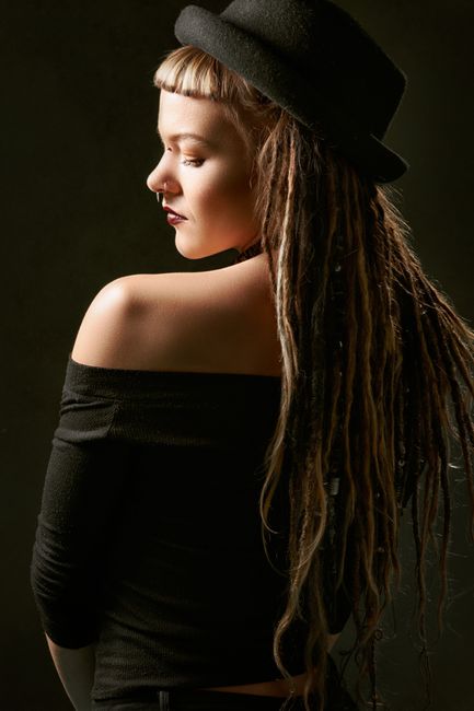 Portrait of a stylish woman in a black dress and dreadlocks, exuding elegance and fashion.