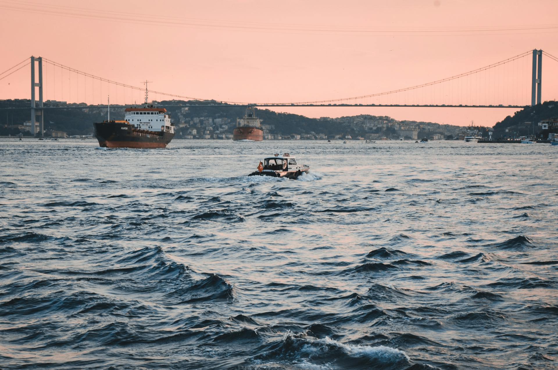 Scenic view of boats navigating the Bosphorus Strait at sunset with a prominent bridge.