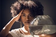 这幅优雅的肖像描绘了一位留着刘海的女人，在室内手持鱼缸