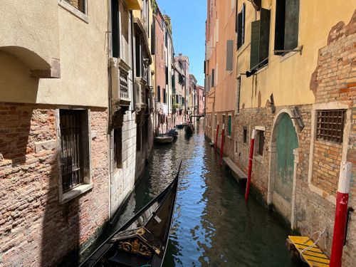 Free A narrow canal in Venice, Italy, flanked by historical buildings and featuring a gondola. Stock Photo