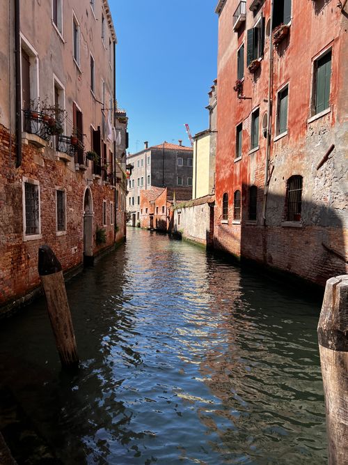 Free Beautiful view of a Venetian canal with colorful historic buildings and clear blue sky. Stock Photo