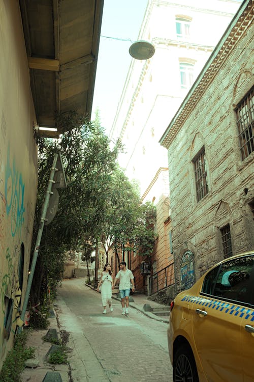 A yellow taxi is parked in a narrow alley