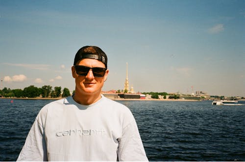 A man in a white shirt and sunglasses standing on a boat