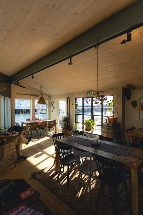 Free Sunlight pours into a Scandinavian style café with wooden decor and cozy seating arrangement. Stock Photo