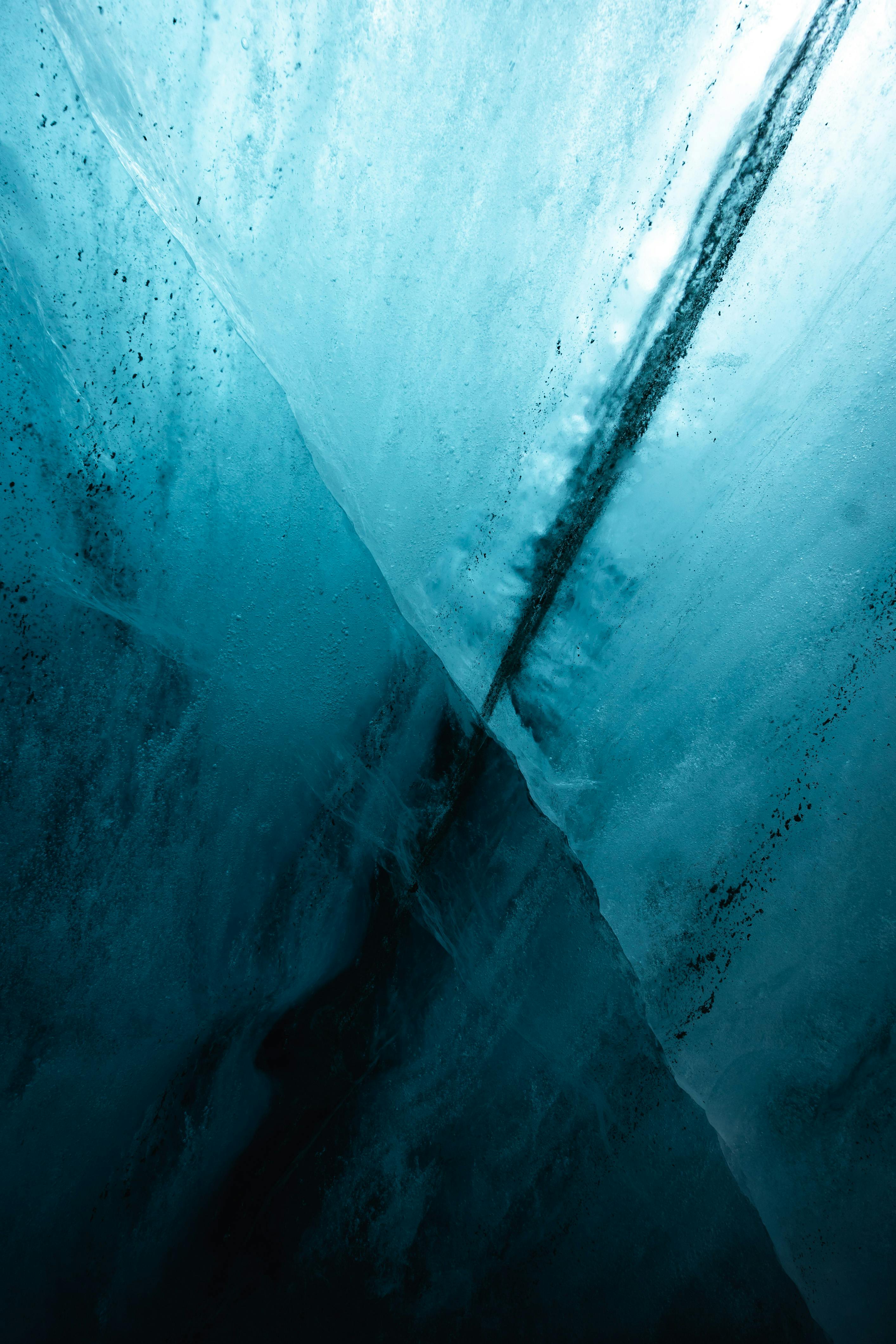 Abstract view of ice with deep cracks showcasing blue tones and textures.