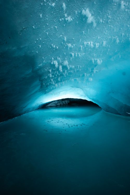 Free Explore the beautiful and mysterious atmosphere inside a blue ice cave with a frozen surface. Stock Photo