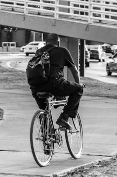 Back view of a man biking on an urban sidewalk in León, Mexico. Black and white photography.